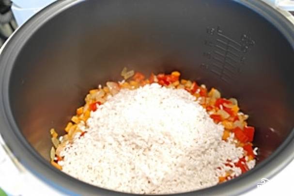 Засыпьте рис, посолите, поперчите, разровняйте лопаткой. Налейте воды так, чтобы она прикрывала поверхность риса на 1 сантиметр.
Готовьте на режиме "Плов" или "Рис"  полчаса. Попробуйте рис - если он еще жесткий, готовьте еще 10-15 минут. 