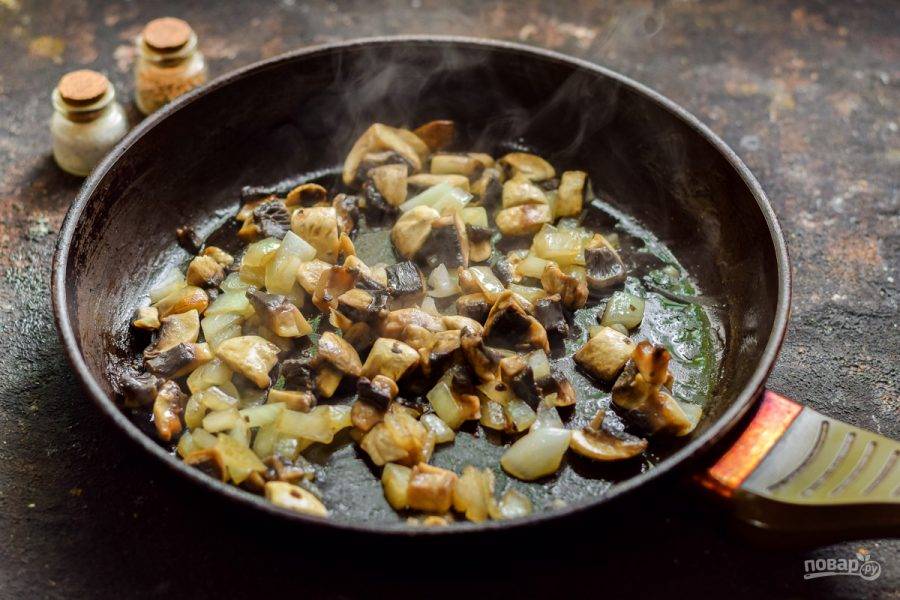 В сковороде разогрейте сливочное и растительное масло, выложите лук и грибы, жарьте ингредиенты 3-4 минуты, до румяности.