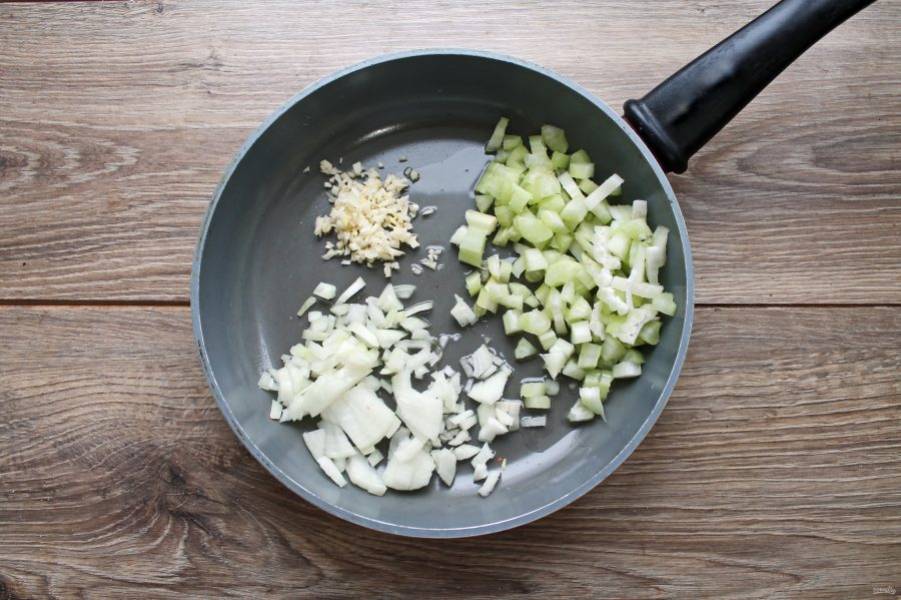 В сковороду налейте растительное масло и выложите нарезанные репчатый лук, сельдерей и чеснок.