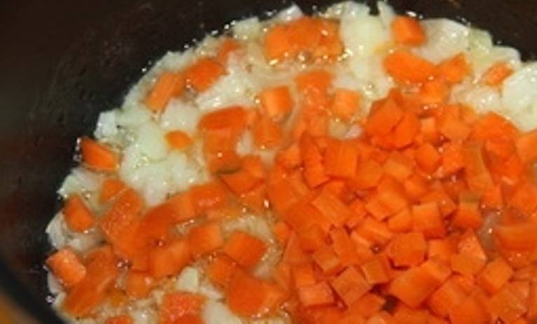 Луковицу мелко порежьте и пассируйте в кастрюле с толстым дном. Туда же добавьте порезанную кубиками морковь. Все вместе обжарьте.