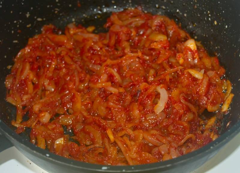 Выкладываем его на сковороду с топленым маслом и жарим до прозрачности, потом добавляем к луку столовую ложку томатной пасты, перемешиваем и жарим еще 3-4 минуты.