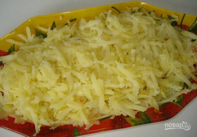 В прямоугольную салатницу наливаем немного майонеза (распределив его по поверхности), сверху выкладываем слой вареного тертого на крупной терке картофеля.