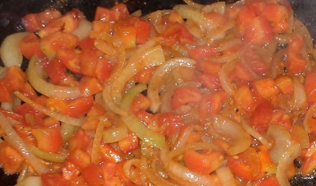Также нужно приготовить зажарку. Для этого мелко нарежьте лук и помидоры. Затем обжарьте лук до золотистого цвета, добавьте помидор и томатную пасту, жарьте еще 2 минуты.