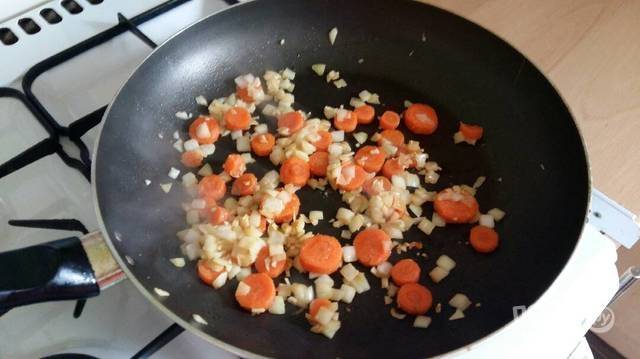 В сковороде обжарьте в масле морковь кружками и измельчённый лук с чесноком до мягкости.