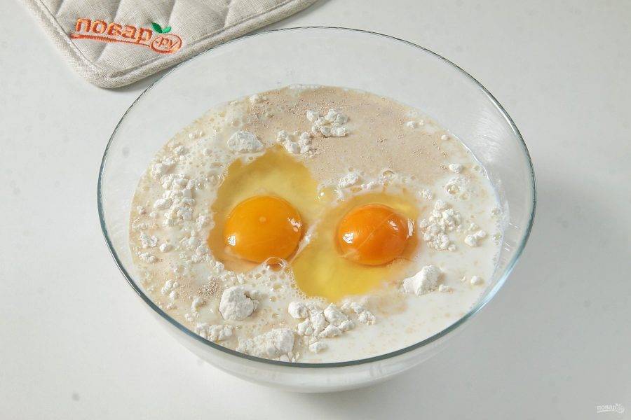 Влейте теплое молоко и добавьте два яйца.