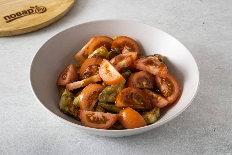 Переложите баклажаны в глубокую миску. Добавьте нарезанные дольками помидоры. Полейте соусом и перемешайте.