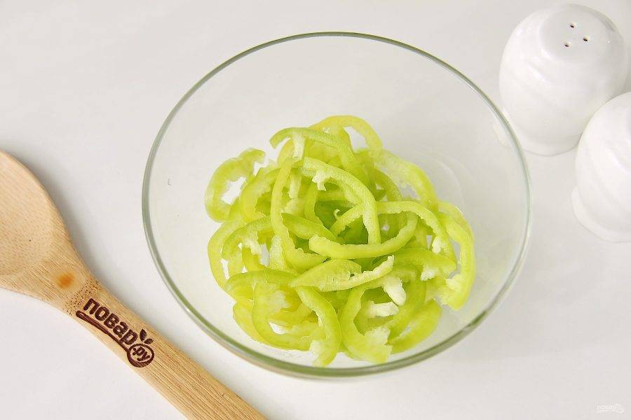 Перец очистите от семян, нарежьте небольшой соломкой и сложите в салатник или глубокую миску.
