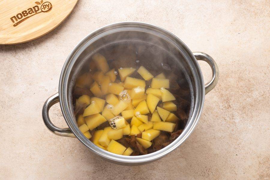 Картофель помойте, очистите и нарежьте кубиками среднего размера. Добавьте в кастрюлю.