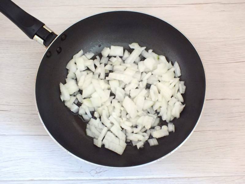 Сначала приготовьте начинку. Для этого нарежьте лук мелким кубиком и обжарьте до готовности на растительном масле.