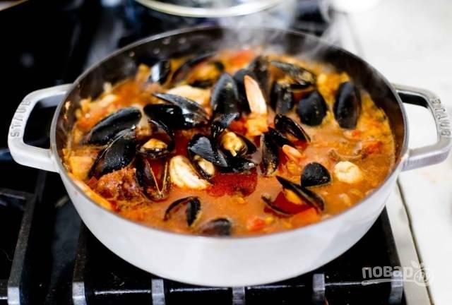 3. Выложите в кастрюлю нарезанный кубиками помидор, рыбу и морепродукты. Добавьте по вкусу соль и перец. Томите на среднем огне около 10-15 минут до готовности.