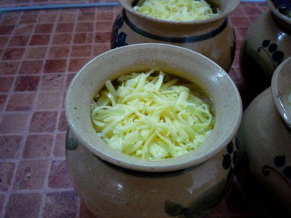 Сверху соус обильно посыпаем тертым на крупной терке сыром, ставим горшочки в разогретую до 180 градусов духовку.  