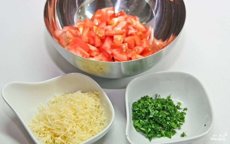 8. Подготовьте овощи для подачи блюда. Помойте помидоры и зелень. Помидоры нарежьте мелкими кусочками. Зелень порубите. Натрите сыр на мелкой терке.