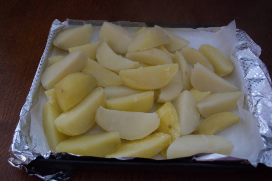Как только картофель закипит, добавьте в воду соль. Варите около 5 минут. Выключите. Слейте полностью воду. Противень застелите фольгой. Уложите на него недоваренный картофель.