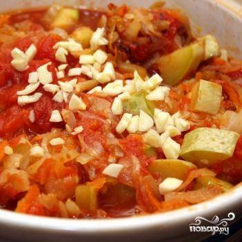 5 минут тушим капусту с кабачками в томатном соусе, после чего добавляем в сковороду мелко нарезанный чеснок, обжаренные лук и морковь. Перемешиваем.