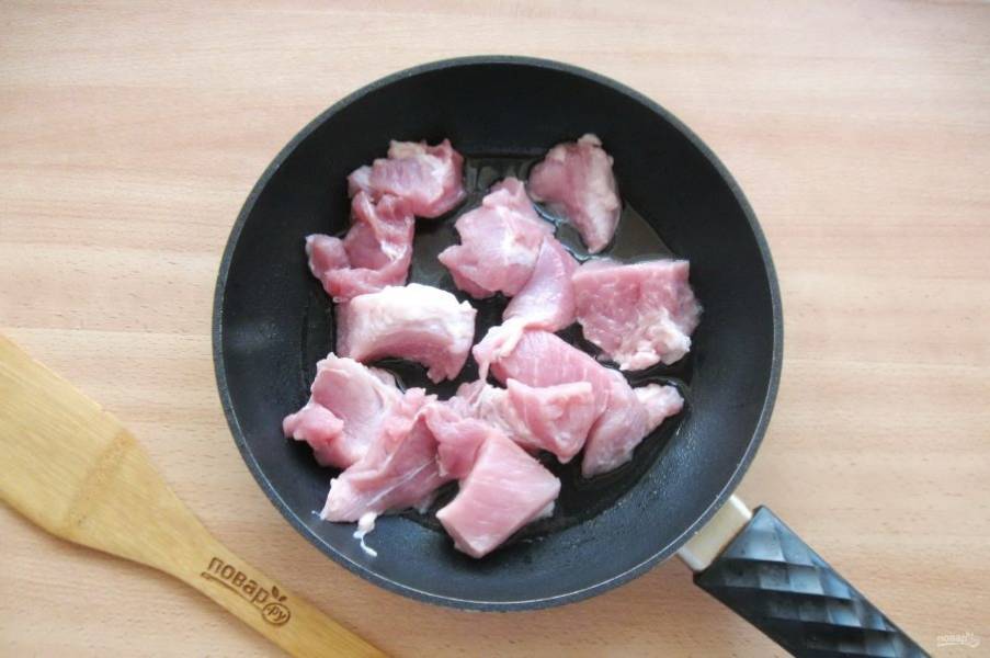 Мякоть свинины порежьте небольшими кусочками и выложите в сковороду с подсолнечным маслом.