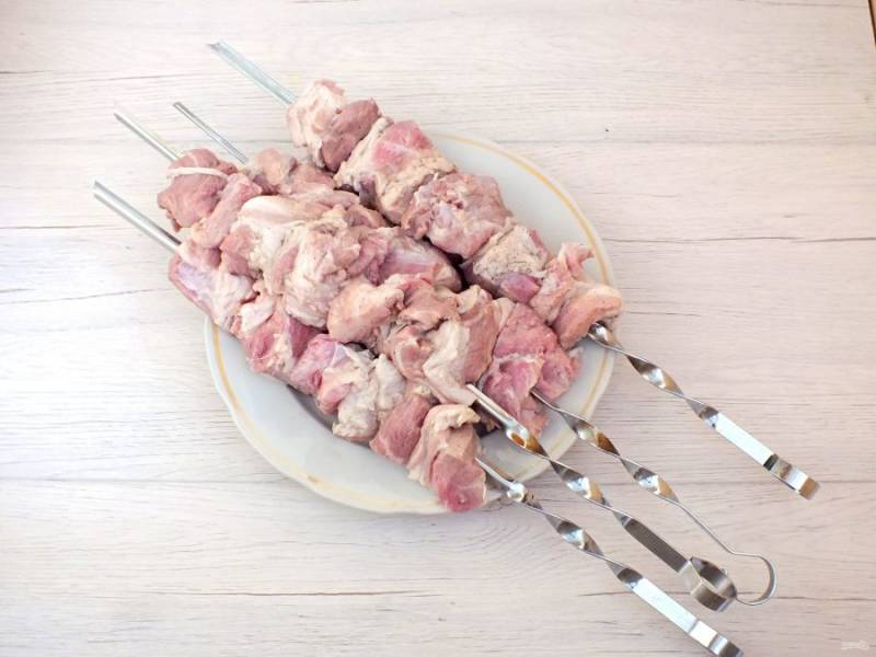 По истечении времени маринования, нанизайте мясо на шампуры, чередуя колечками лука (по желанию).