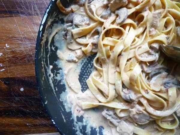 Соедините пасту и курицу с грибами на сковороде, перемешайте и отставьте сковороду с огня.