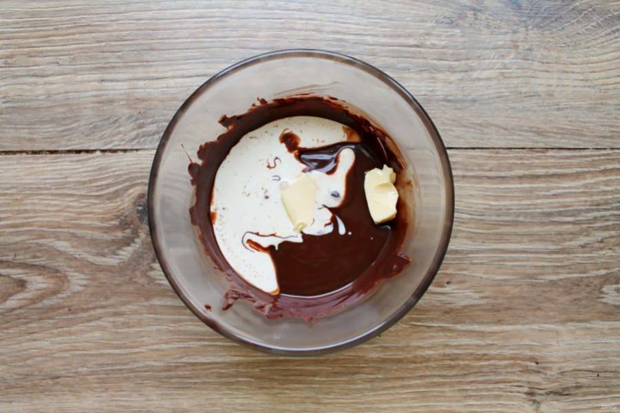 Добавьте в миску с шоколадом и сливками сливочное масло и перемешайте до однородности.