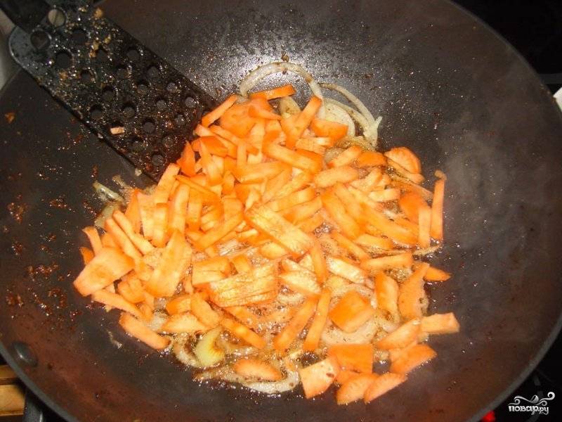 Морковь нарезаем соломкой и выкладываем к луку, обжариваем еще 1 минуту.
