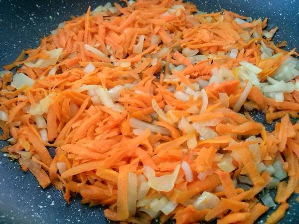 Займитесь начинкой: очистите  морковь и лук, лук нарежьте маленькими кусочками, морковь натрите на крупной терке. На сковороде разогрейте растительное масло и до прозрачности спассеруйте лук, добавьте  морковь, закройте крышкой и тушите на медленном огне минут пять.