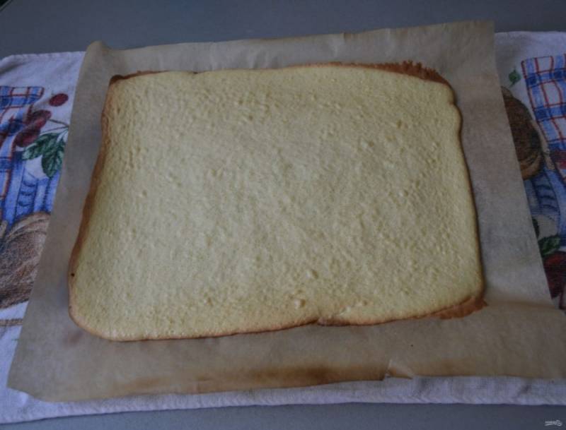 Выложите тесто на лист пергамента для выпечки, разровняйте, выпекайте 10-15 минут при температуре 180 градусов. Пока бисквит горячий, его лучше сразу отделить от пергамента, это легко сделать, если выложить готовый бисквит на влажную салфетку. 