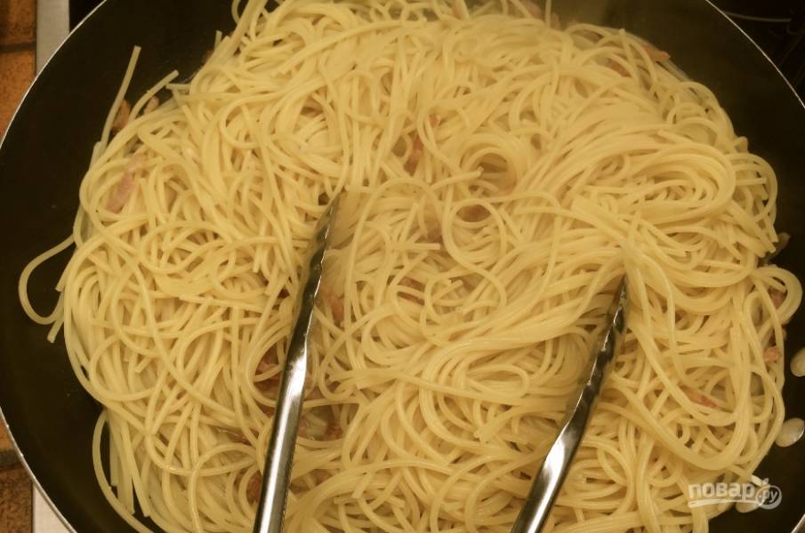 2. Дальше добавим отваренные спагетти к бекону. Перемешаем тщательно, немножко поджарим. 