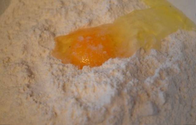 Для начала мы просеиваем в миску муку, смешиваем ее с солью и добавляем в миску яйцо и воду. 