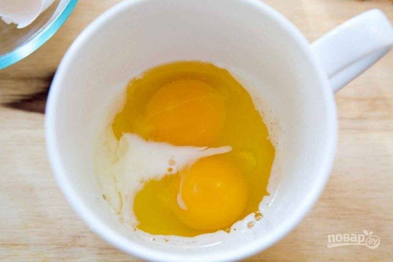 1.	Смажьте чашку растительным маслом (любым по вкусу), чтобы омлет не приставал к ее бокам. Вбейте в чашку 2 яйца, влейте столовую ложку молока.