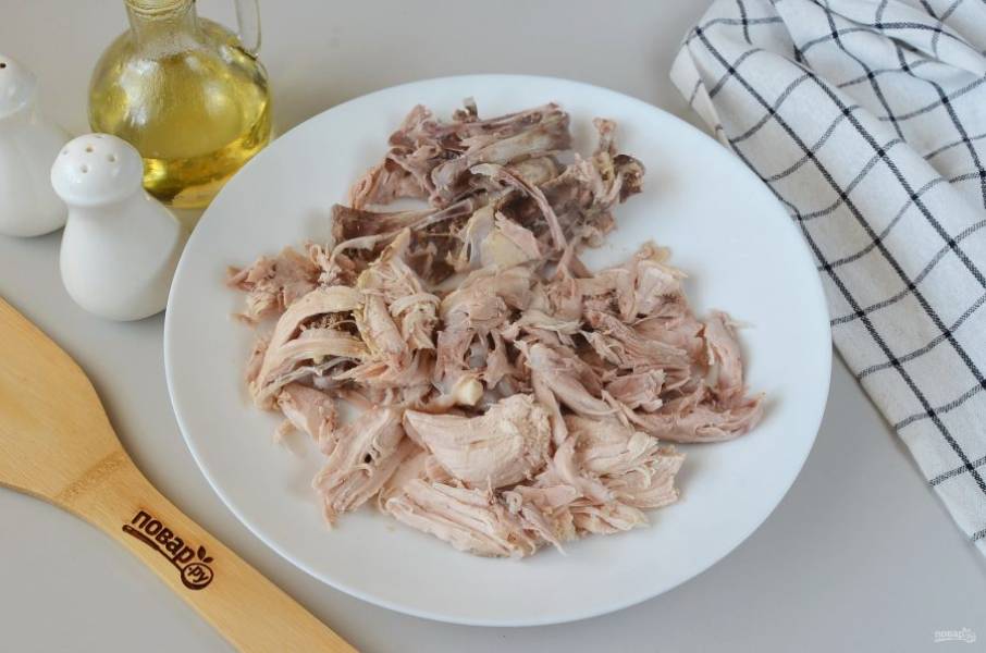Достаньте курицу из бульона, отделите мясо от костей, мясо измельчите и верните в бульон.