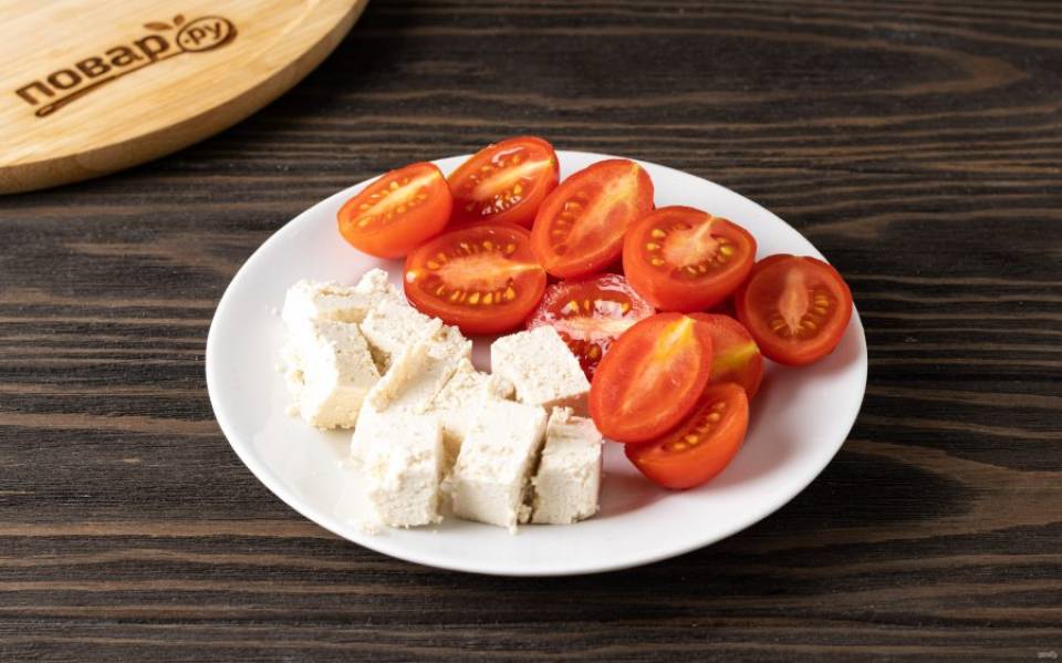 Сыр нарежьте на небольшие кубики, а помидоры черри помойте и разрежьте на 2-4 части.