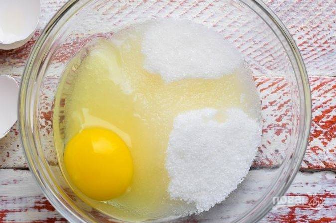 Вбейте сырое куриное яйцо в стеклянную миску, высыпьте к нему сахар. Взбивайте яйца с сахарной пудрой на максимальной скорости миксером, пока масса не посветлеет и не увеличится в объеме. 