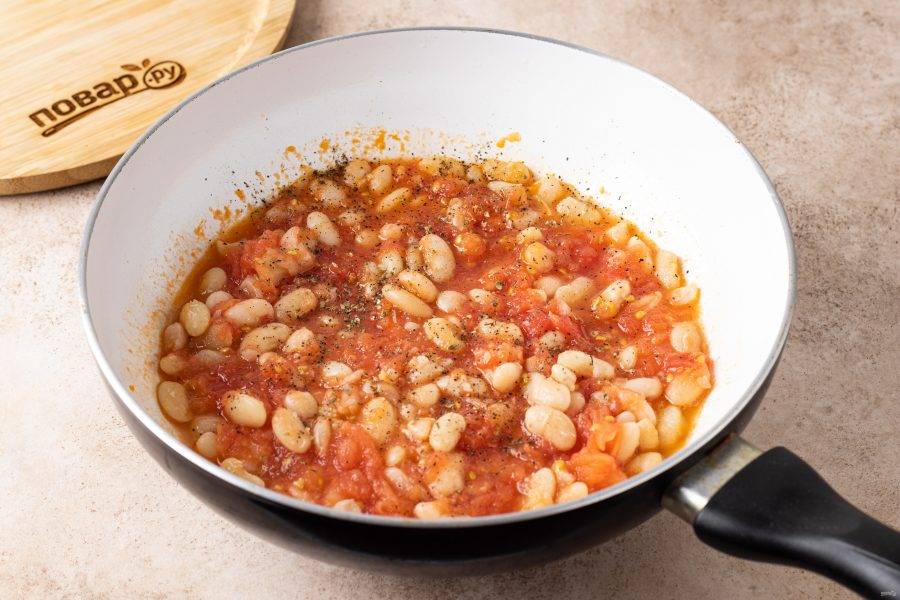 Следом добавьте помидоры, чёрный молотый перец и сушёные итальянские травы. Томите фасоль примерно полчаса, пока томаты не загустеют. В конце посолите по вкусу.