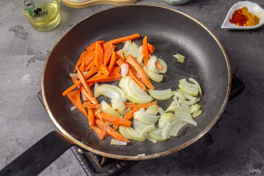 В сковороде разогрейте растительное масло. 
Лук и морковь очистите. Лук нарежьте тонкими перьями, морковь — соломкой. Отправьте овощи в сковороду и жарьте пару минут, до мягкости. 