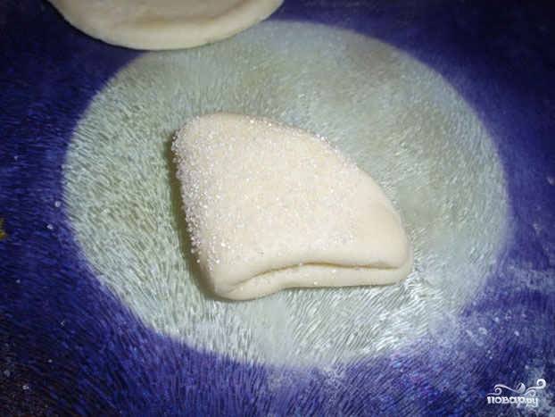 3.	В миску насыпаем сахар, каждый кружочек с одной стороны обмакиваем в сахар, сворачиваем пополам, а затем еще пополам. Затем опять обмакиваем в сахар. 