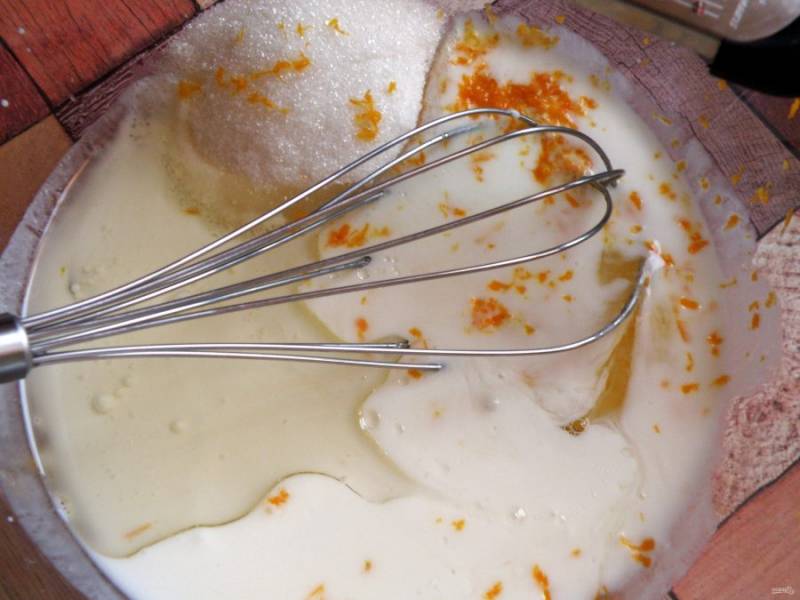 Смешайте венчиком в просторной миске кефир, соль, сахар, яйца, масло растительное  и цедру апельсина. 