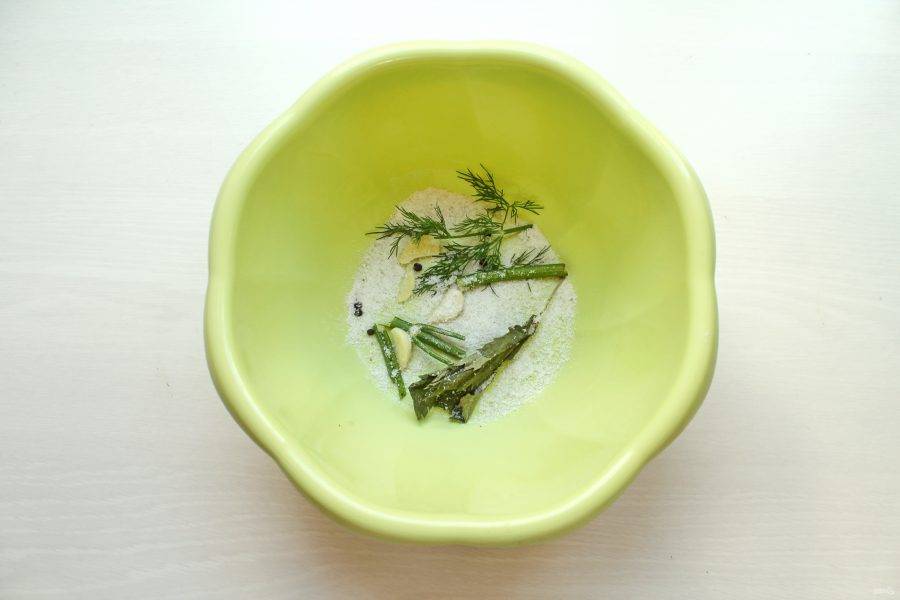 На дно посуды, где будете солить маслята, насыпьте тонкий слой соли, и выложите часть специй и зелени.