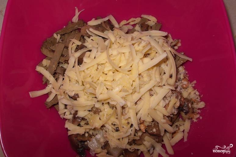 В глубокую емкость кладем: печень, остывшие грибы с луком, орехи, порезанные колечки ананаса. Сверху присыпаем тертым сыром.