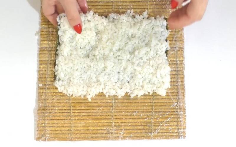 Готовим роллы: на половину листа нори выложите рис и распределите его равномерным слоем.
