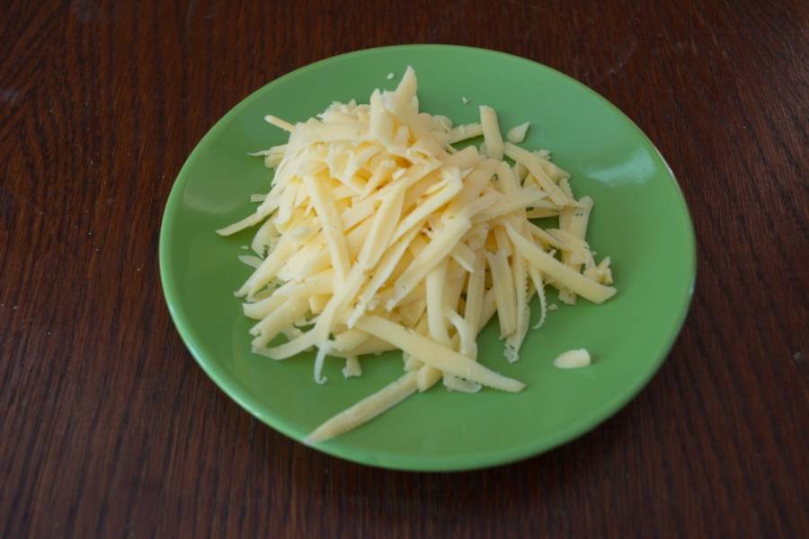 Натрите на терку твердый сыр. Я использую терку с крупными дырками, чтоб сыр не сгорел в духовке. Более крупные кусочки сыра будут дольше запекаться.