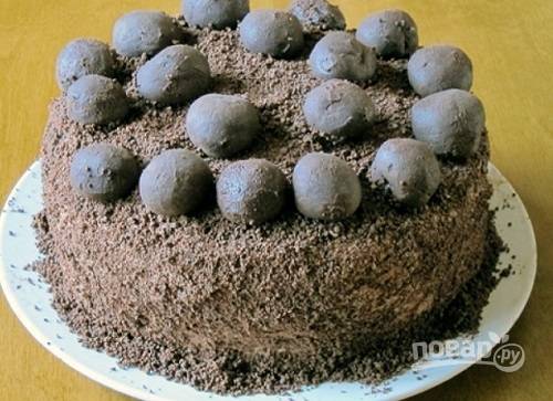 Шоколад предварительно заморозим, а затем натраем на терке. Посыпаем им торт со всех сторон, украшаем кофетами. Даем тортику настояться пару часов.