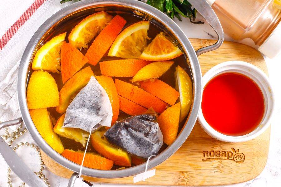 Поместите емкость на плиту и отварите примерно 3 минуты с момента закипания, чтобы апельсиновая нарезка отдала жидкости свой аромат и вкус. Добавьте пакетики черного чая.