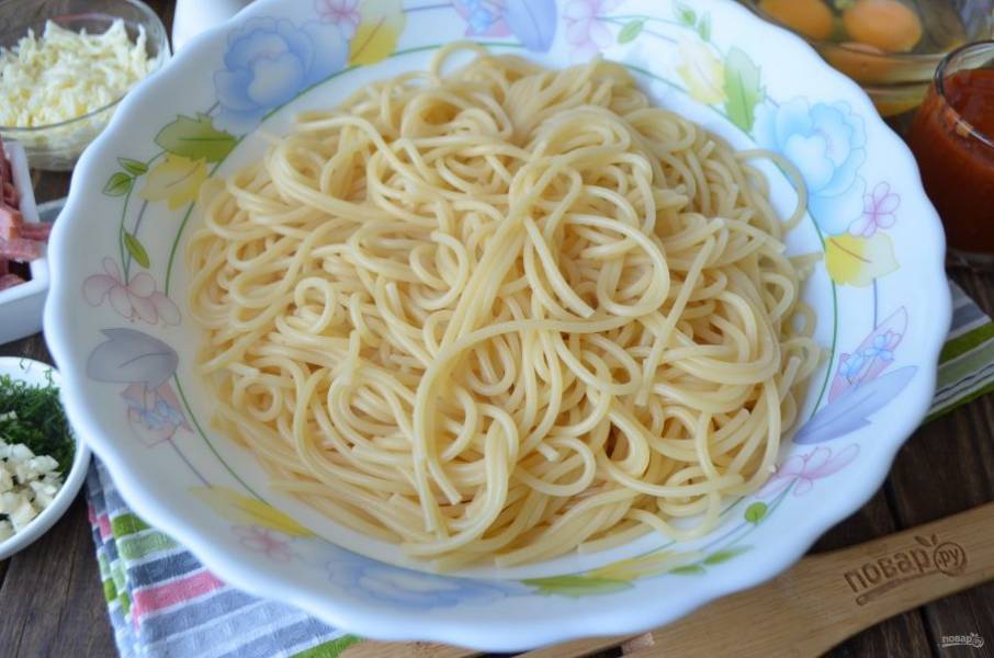 Отварите спагетти до готовности, откиньте на дуршлаг. Переложите в глубокую посудину.