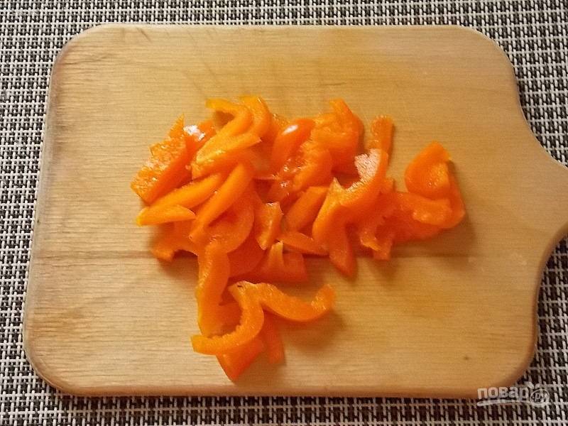 Перец очистите от семян и порежьте соломкой. Поджарьте тертую морковь и резанный лук на растительном масле в течение 5 минут.