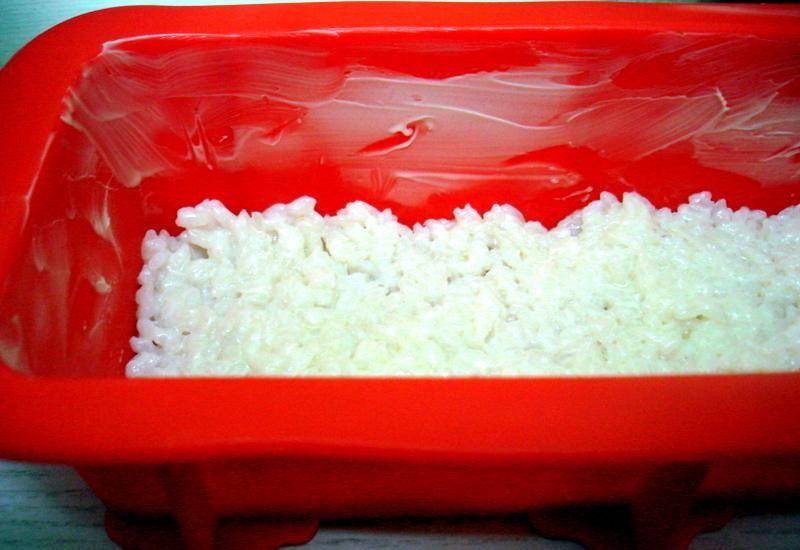 Выкладываем в форму 1/3 часть всего риса, равномерно распределяем по поверхности. 
