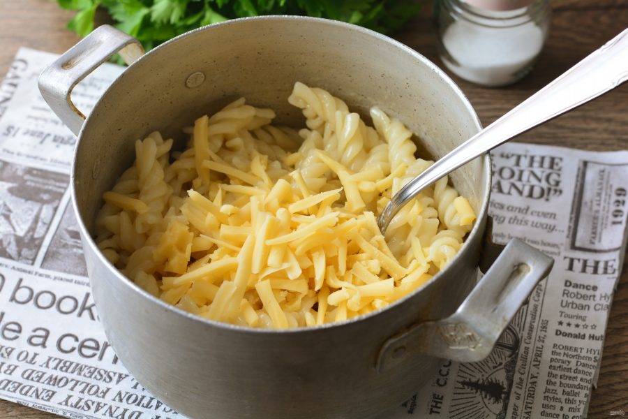 Добавьте сливочное масло и всыпьте сыр в горячие макароны.