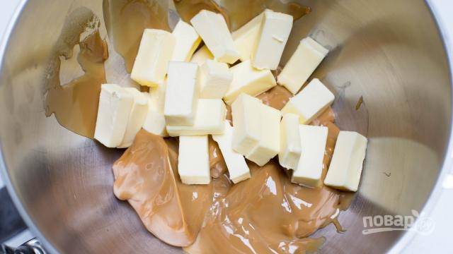 6.	Оставшееся сливочное масло нарежьте кусочками и выложите в миску, к нему добавьте вареное сгущенное молоко. 