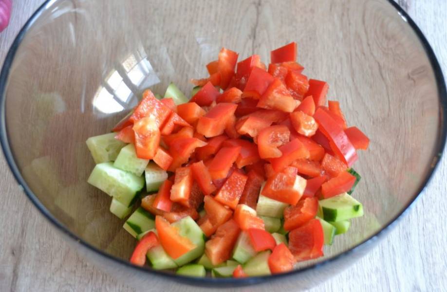 Нарежьте небольшим кубиком огурцы и болгарский перец, выложите в салатник.