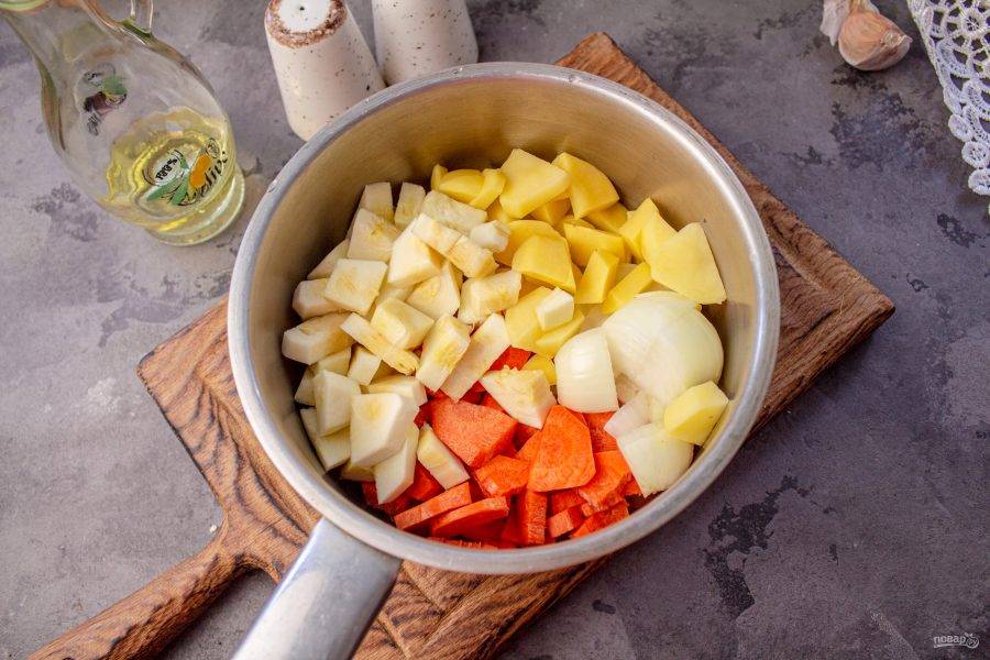 В кастрюлю выложите очищенные и нарезанные на небольшие кусочки лук, морковь, картофель и кабачок. 