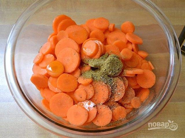 2.	Нарежьте морковь тонкими кружочками. Выложите овощ в миску и влейте столовую ложку растительного масла, тмин, соль, молотый перец.