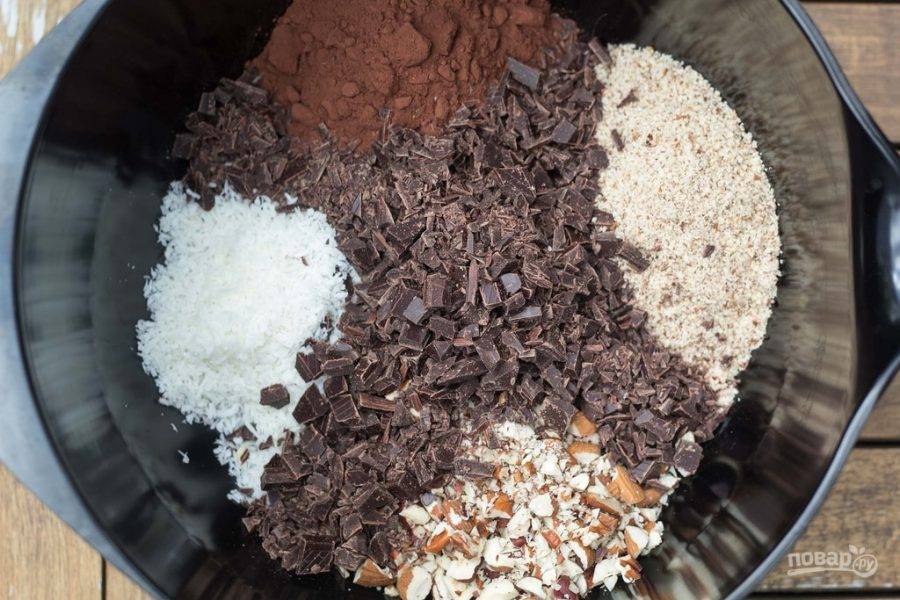 2. Остальные орехи и шоколад нарежьте кусочками. Смешайте их вместе с какао, разрыхлителем, получившейся мукой, солью и кокосовой стружкой.